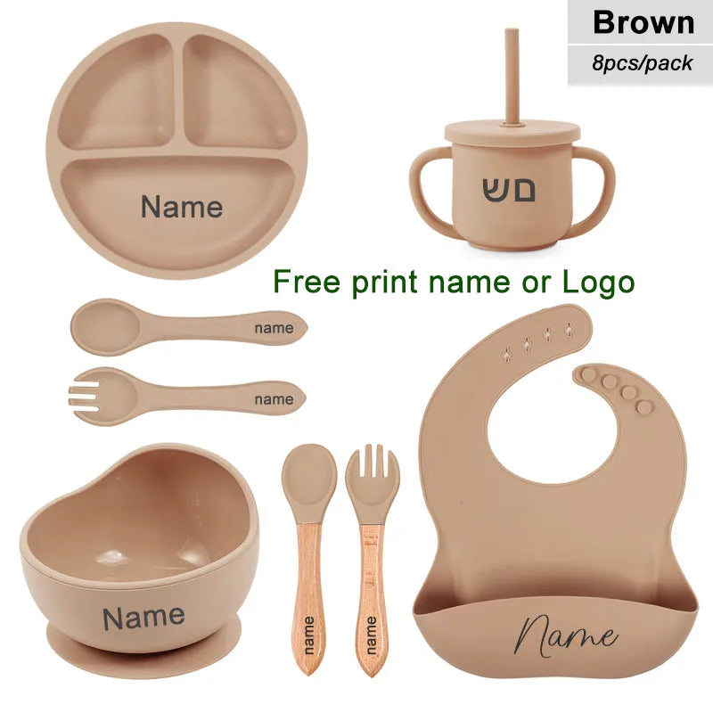 Set of brown baby utensils including plate, cup, bowl, spoons, and bib with customizable name or logo.