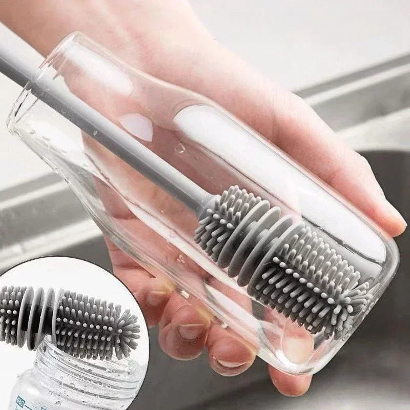 Hand holding a clear plastic bottle with a gray brush inside, against a neutral background.