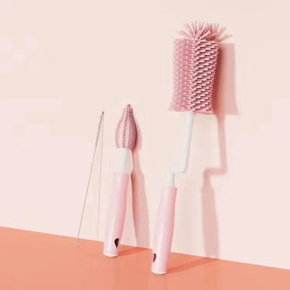 Three cleaning brushes with different bristle designs on a peach and pink gradient background