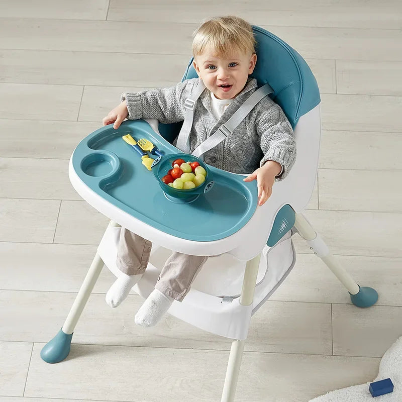 Child sitting in a blue and white high chair with a tray, eating fruits and vegetables.