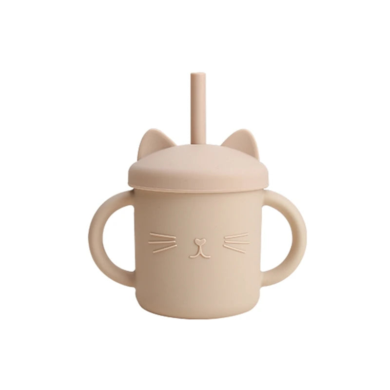 Beige sippy cup with cat ears and face design on a white background