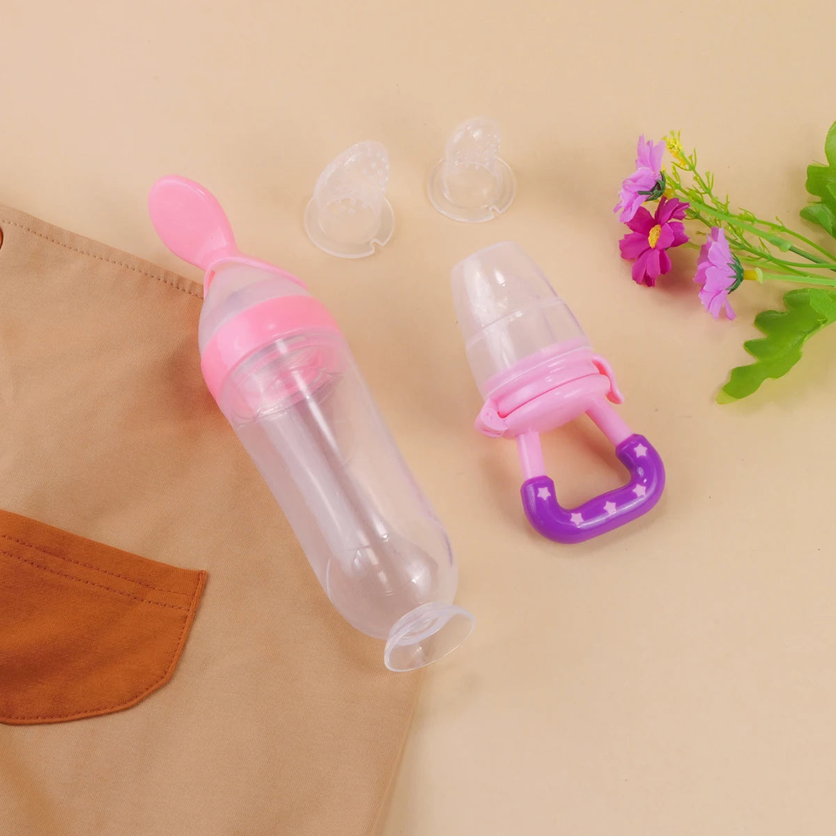 Baby feeding bottle with pink and purple accents on a beige background