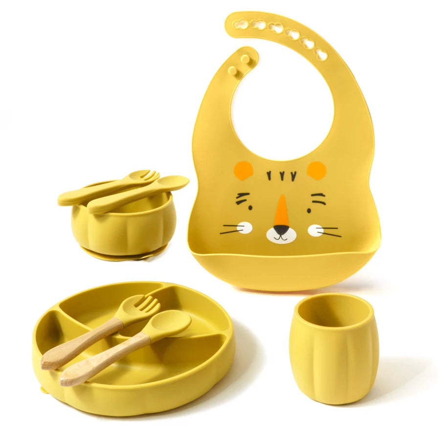 Yellow children's dining set with bib, bowl, cup, and utensils on a white background