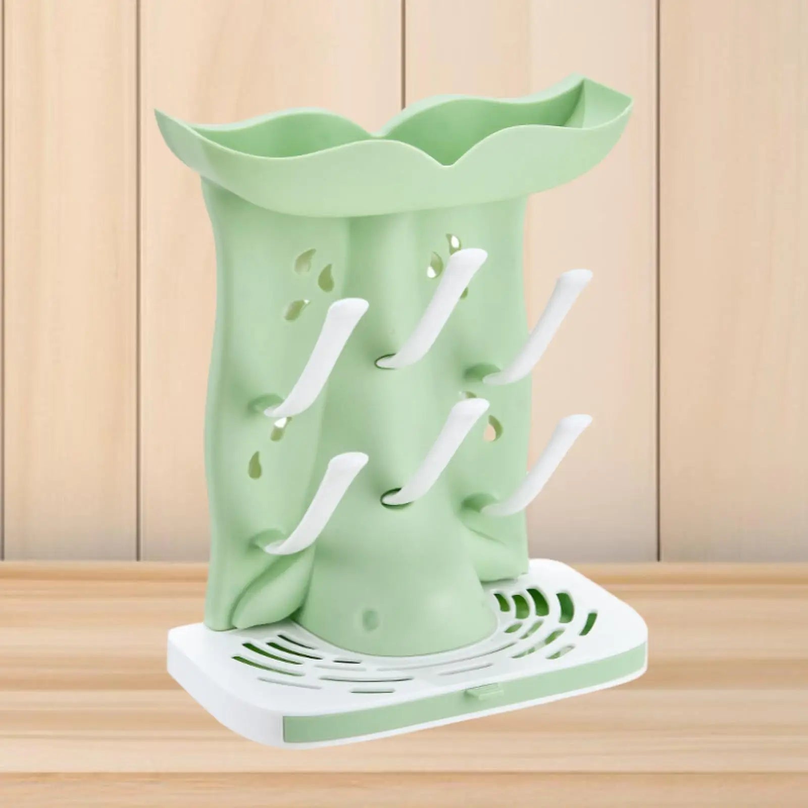 Green and white dish drying rack on a wooden surface with a light wood panel background