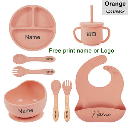 Children's dining set with pink items including a plate, cup, bowl, utensils, and bib on a white background.