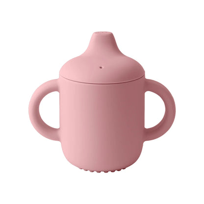 Pink sippy cup with a lid on a white background