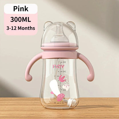 Pink baby bottle with handles on a wooden surface and beige background